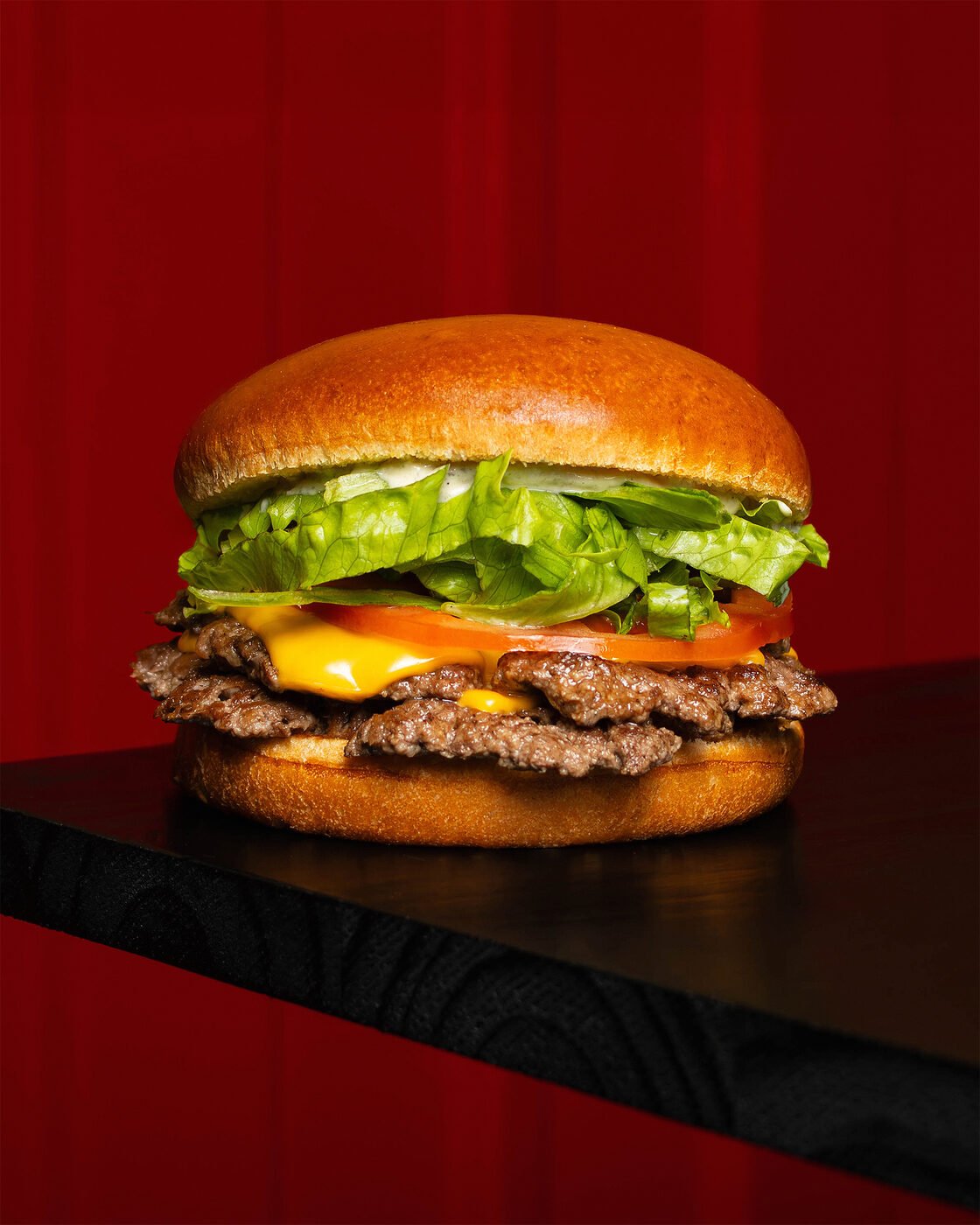 Cheeseburger sobre bancada preta com fundo vermelho